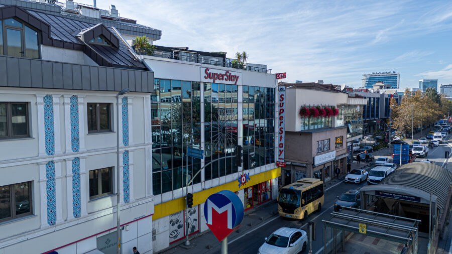 Cam cepheli otel binası, önünde T4 Topçular tramvay durağı ve metro tabelası